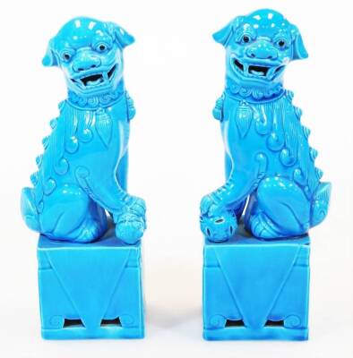 A pair of late 20thC Chinese dog of fo ornaments, in turquoise glaze on rectangular bases, each with their paw on a pierced ball, 26cm high. (2)