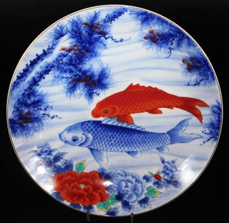 A 20thC Japanese porcelain charger, of circular form, decorated with fish and flowers, predominantly in orange, blue and yellow, marks beneath, 40cm diameter.