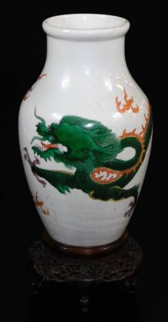 A Chinese porcelain vase, decorated with an enamel dragon, on a heavily carved wooden base, 28cm high.