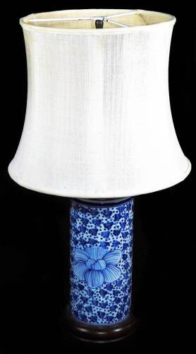 A Chinese porcelain table lamp, of cylindrical form with wooden mounts decorated with flower heads and dots, with modern electric feature, 47cm high, and shade.