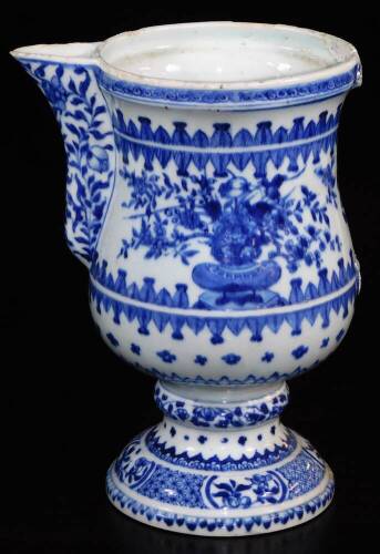 A 18thC blue and white porcelain ewer, with shaped spout, bellied circular body, inverted stem and domed foot, profusely decorated with vases of flowers in upper geometric pattern, with handle lacking, 25cm high.