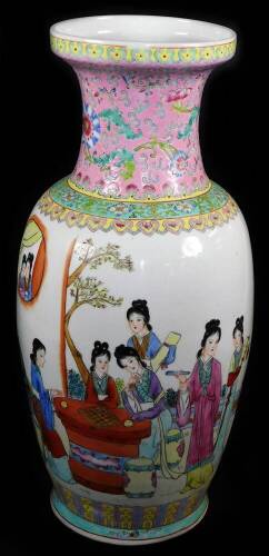 An early 20thC Chinese famille rose baluster vase, enamelled with women playing games at a table, inscribed poem to the reverse, the neck, profusely decorated with flowers on a pink ground, lappet borders, four character Qianlong mark to the base, 43cm Hi
