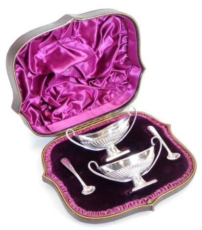 A pair of Victorian silver open salts, partially gadrooned with strap handles on rectangular feet, with spoons, Sheffield 1886, 10cm wide, 2oz. (cased)