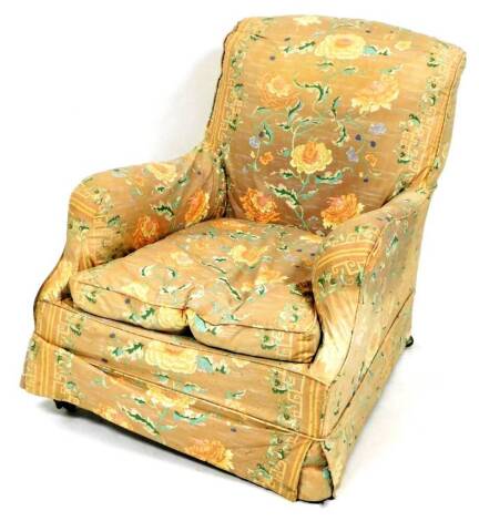 A Victorian deep seated low armchair, in the manner of Howard & Sons, with floral loose covers, turned forelegs and brass cup castors.