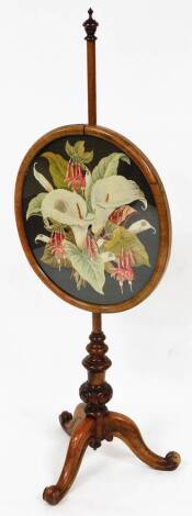 A Victorian walnut pole screen, with oval floral woolwork panel, and tripod base.