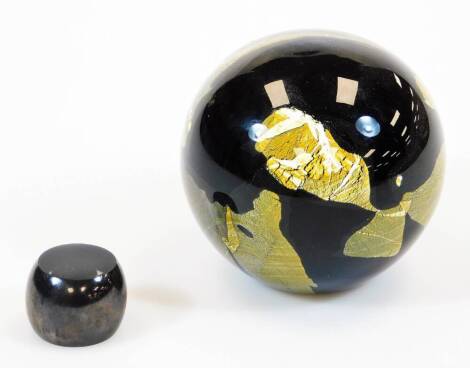 A 20thC studio Our Glass paperweight of globular form, in black and gilt colour way, Ourglass style, signed, 7cm high, and a similar style stand.