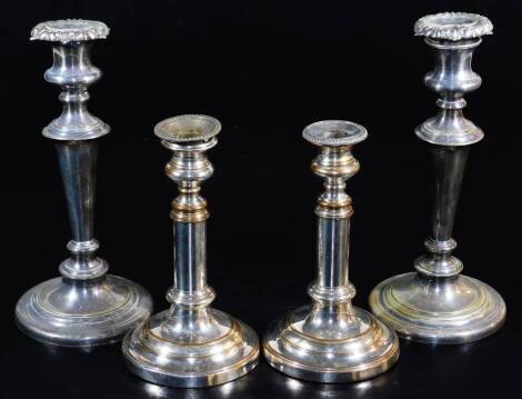 A pair of old Sheffield plate telescopic candlesticks, of cylindrical form on stepped circular bases, when lowered 22cm high and a further pair of silver plated candlesticks with elaborate scroll and floral sconces, tapering stems and circular stepped fee