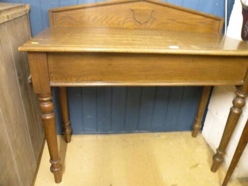 A Victorian oak side table with a raised back on turned legs<br