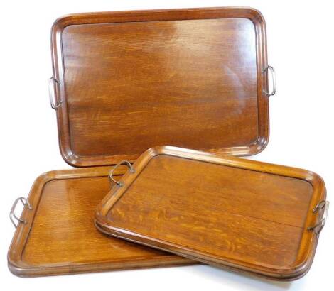 A set of three graduated Edwardian trays, each with metal handles, of oblong form, 55cm wide, etc. (3)