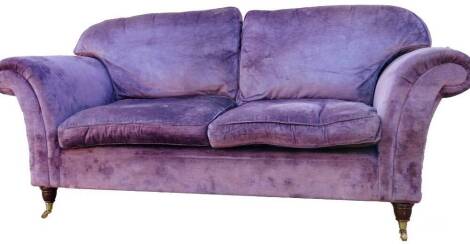 A 20thC two seater settee, with turned front legs, terminating in brass castors, with shaped arms, in purple velvet style material, compressed saber back legs, 79cm high.