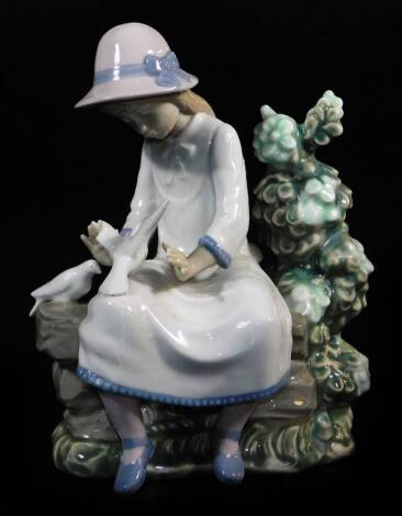 A Nao by Lladro figure, of a girl seated aside dove and shrubs, marked beneath, 23cm high.