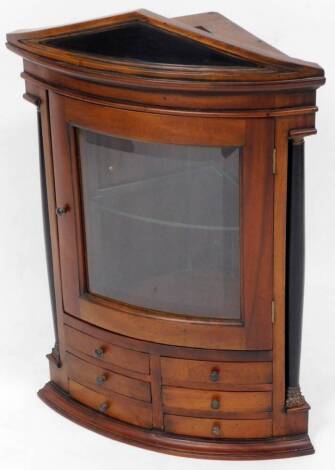 A 20thC mahogany hanging curved corner cupboard, with glazed door raised above six spice drawers on a moulded base with a pedimented top, 75cm high, 58cm wide, 35cm deep.