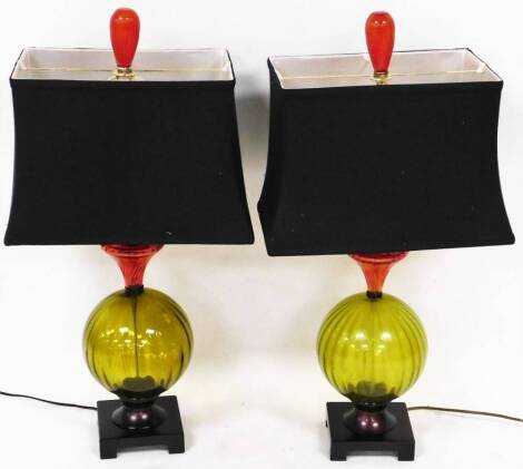 A pair of table lamps, in green glass on platform bases with blue shades surmounted by red bulbs, 81cm high. (2)