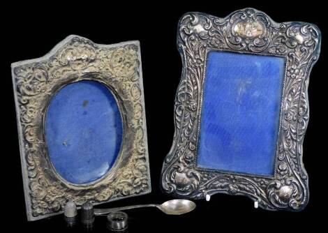 An Edwardian silver photograph frame, of shaped rectangular form, heavily repousse decorated with scrolls and flowers with a vacant cartouche, Birmingham 1908, 22cm high, and another easel back, a teaspoon tooth and two thimbles, etc. (a quantity, AF)