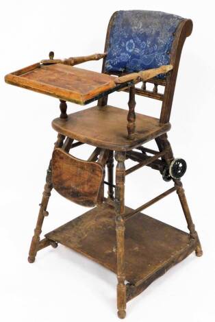 An early 20thC child's elm high chair, with tray front and foot rest on wheeled back with a galleried desk set with abacus, 47cm high.