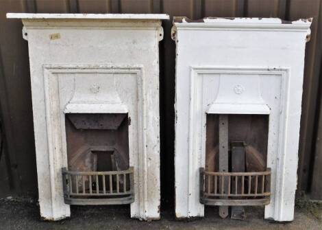 A pair of Victorian cast iron fireplaces, each of rectangular form in white, with central openings and front removable grates, 107cm high, 73cm wide, 12cm deep.