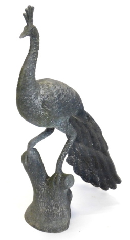 A bronzed metal peacock garden ornament, in oriental style, standing on a tree stump, 86cm high.