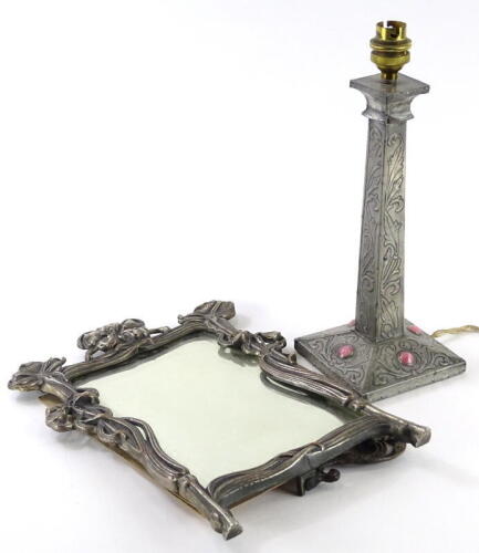 A late 19thC Art Nouveau style silver plated copper dressing mirror, with a bevelled plate and a strut support to the reverse, stamped 236, 35cm x 24.5cm and a pewter and wooden table lamp base, inset with pink glass roundels (2).