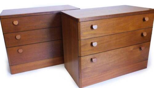 A pair of Stag teak chests of drawers, each with rounded corners above three graduated drawers, with shaped wooden handles, on a plinth, 63cm high, 82cm wide, 43.5cm deep.