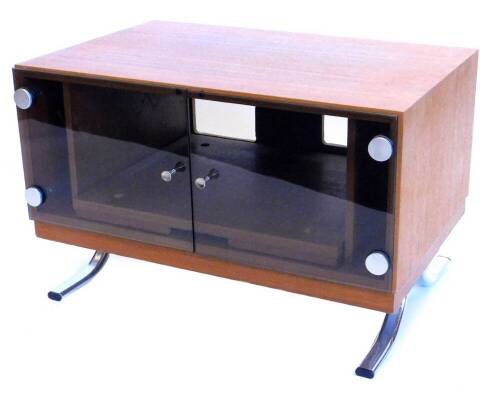 A 1970's/80's Danish style teak television stand, with two smoked glass doors, each with brushed finish metal and plastic hinges, enclosing a pull out section for a video recorder, on four plated splayed legs, 44cm high, 69cm wide.