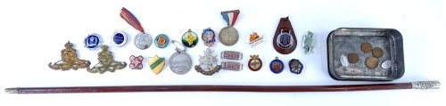 A collection of cap badges, other badges, a regimental type swagger stick, etc.