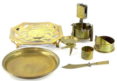 A collection of brass Trench Art, to include a smoker's stand with match strike, inscribed France 1919, a paper knife, an ashtray suspended with three bullets, a trivet, an ashtray modelled in the form of a cap, etc.