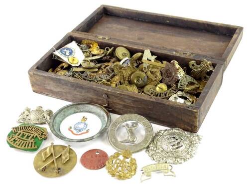 A collection of military cap badges, a small pin tray with Aynsley ceramic insert, an Egyptian souvenir bracelet, other military badges and buttons.