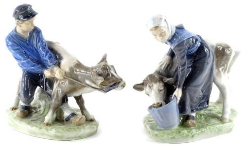 A pair of Royal Copenhagen porcelain figure groups, each modelled in the form of a Farmer, and a Farmer's Wife with a cow, on oval base, green printed and blue handwritten marks, numbered 772 and 779 respectively, 16cm high.