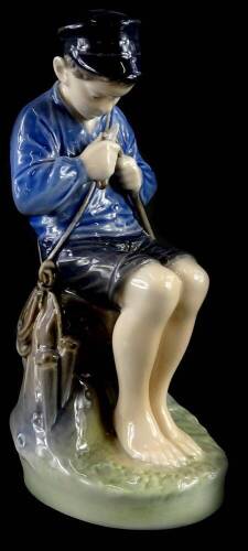 A Royal Copenhagen porcelain figure, model in the form of a young fisherman with a knife, seated on a rock, printed marks and hand decorated marks in blue, numbered 905, 18.5cm high.