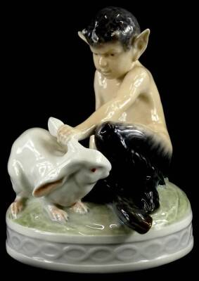 A Royal Copenhagen porcelain figure group, model in the form of a fawn, holding a rabbit, on a circular base, printed marks and handwritten mark in blue, numbered 439, 13.5cm high.