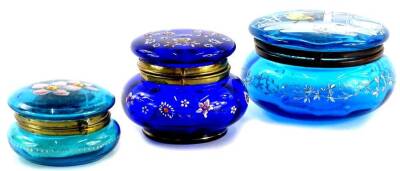 A Victorian blue glass jar and cover, the lid decorated in coloured enamels with birds, in a winter scene, 12cm diameter, and two other similar.