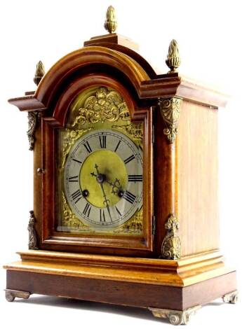 An early 20thC German walnut mantel clock, the arched brass dial with a silver chapter ring, the mahogany case with gilt metal and mounts, 43cm high.