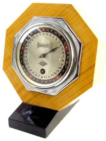 An Art Deco Day Dial calendar, with clockwork mechanism, in figured wooden octagonal case and ebonised stand, with key.