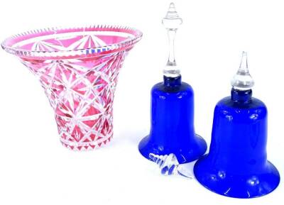 A pair of blue and clear glass ornamental bells, and a cranberry tinted cut glass vase of tapering form. (AF)