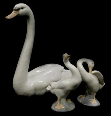 A Lladro porcelain figure of a swan, 21cm high, and two small geese. (3)