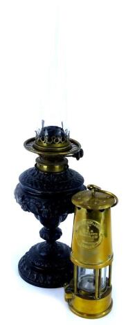 A Victorian ebonised spelter on a lamp base, with brass fitting, 33cm high, a glass chimney and a protector brass oil lamp.