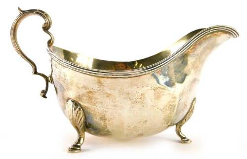 A George V silver sauce boat, of faceted form on three feet with reeded scroll shaped handle, Birmingham 1914, 6½oz.