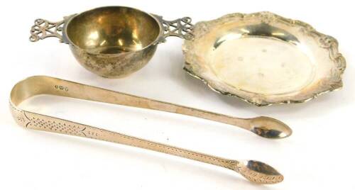 A collection of small silver, to include a small dish with a shaped shell cast border, a two handled pierced wine taster, engraved Won By, and a pair of silver sugar tongs, (3), 5½oz.