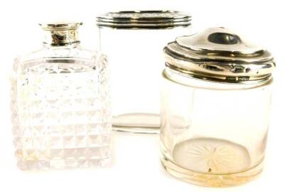 Three silver mounted glass jars, a cylindrical example with domed silver lid, an oval example with engraved lid, and a square section piece with loose fitting lid, various dates and sizes.