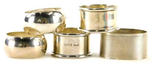 A collection of silver napkin rings, to include a pair of circular shaped pieces, and an oval napkin ring engraved with initials and with engine turned borders, 2½oz overall.