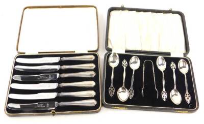 A set of six Arts and Crafts silver teaspoons, with matching sugar tongs, pierced and shaped handle, by Docker and Burn and a set of silver handled dessert knives.