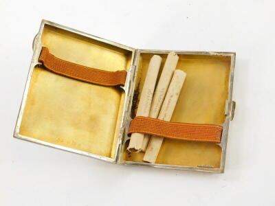 A George V silver cigarette case, with engine turned decoration and a vacant rectangular cartouche, containing three HD and H Wills cigarettes, 2¾oz. - 2