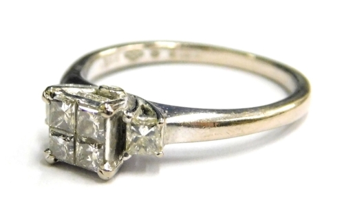 An 18ct white gold diamond set dress ring, with arrangement of four princess cut diamonds on raised centre platform, flanked by a princess cut diamond to each side, and small round brilliant cut diamonds to each side, with Beaverbrooks certificate, totall