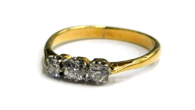 Three stone diamond dress ring, set with three tiny diamonds, each in platinum claw setting, with pierced design shoulders on a yellow metal band, stamped 18ct, ring size M, 2g all in.