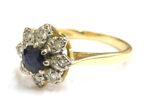 An 18ct gold sapphire and diamond cluster ring, set with round brilliant cut sapphire to centre, surrounded by illusion set tiny diamonds, in a raised openwork setting, ring size O, 4.1g all in.
