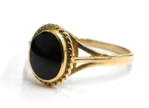 A 9ct gold dress ring, set with polished black stone, with twist design borders and V splayed shoulders, ring size O, 1.6g all in.