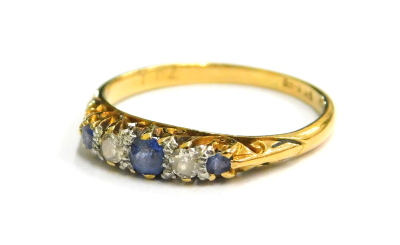 An 18ct gold sapphire and diamond ring, set with three pale blue sapphires and two diamonds, each in claw setting, with scroll design sides, ring size J, 1.8g all in.