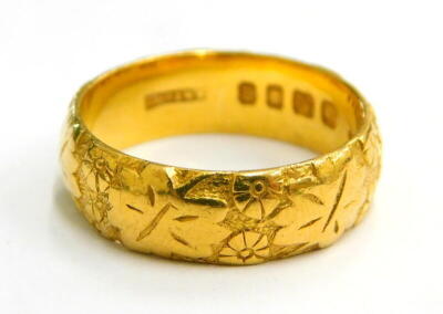 A 22ct gold embossed wedding band, with design of leaves and flowers, of hammered design, ring size N, 7.3g.