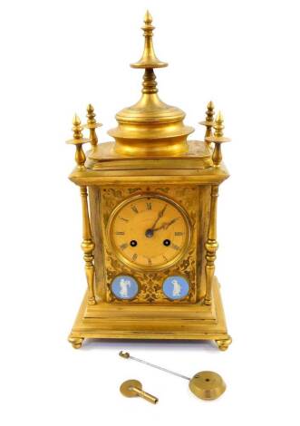 A Howell James & Company brass cased mantel clock, circular dial with engine turned decoration, chapter ring bearing Roman numerals, eight day movement with bell strike, the case of Moorish temple form, foliate engraved and set with Wedgwood blue Jasper r