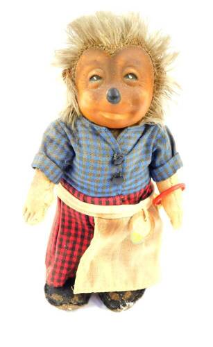 A Steiff 1960's Micki figure, of a hedgehog wearing a blue chequered top and red chequered trousers, with apron, bearing labels, 17cm high.